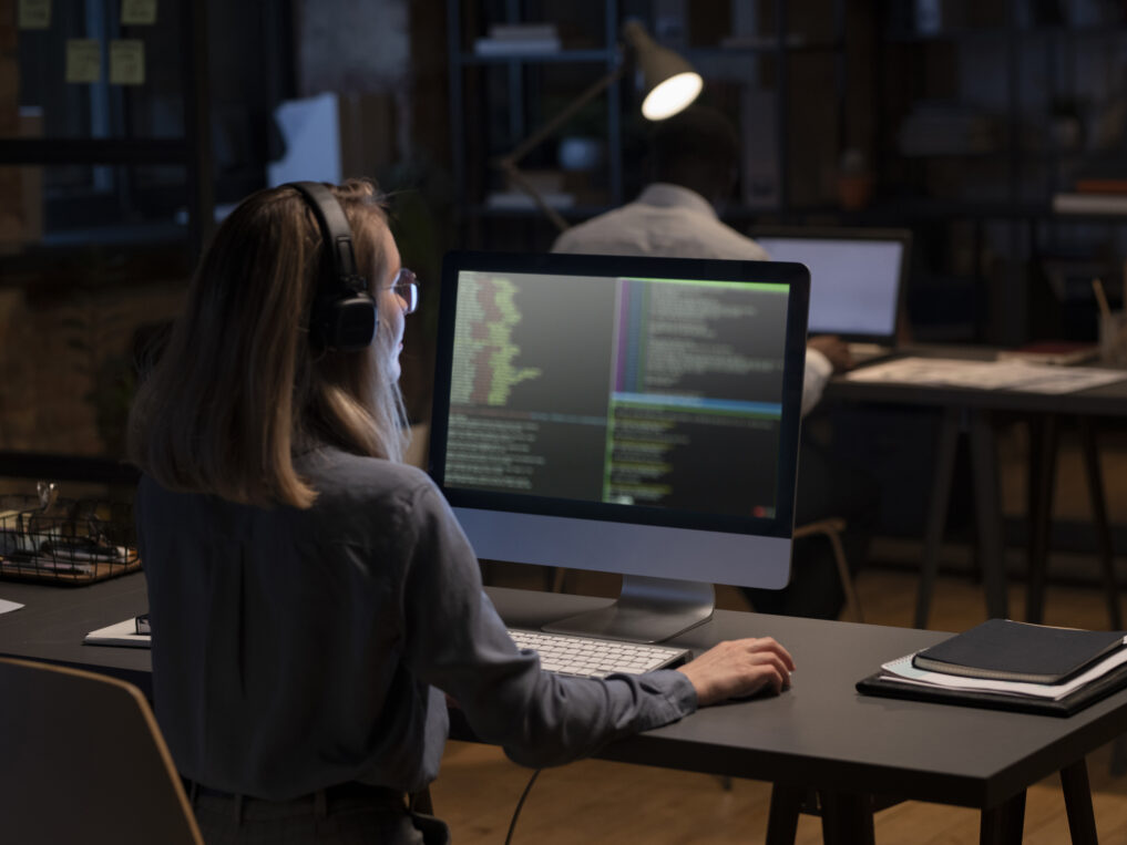 Woman staring at a screen with code while working in an office setting.