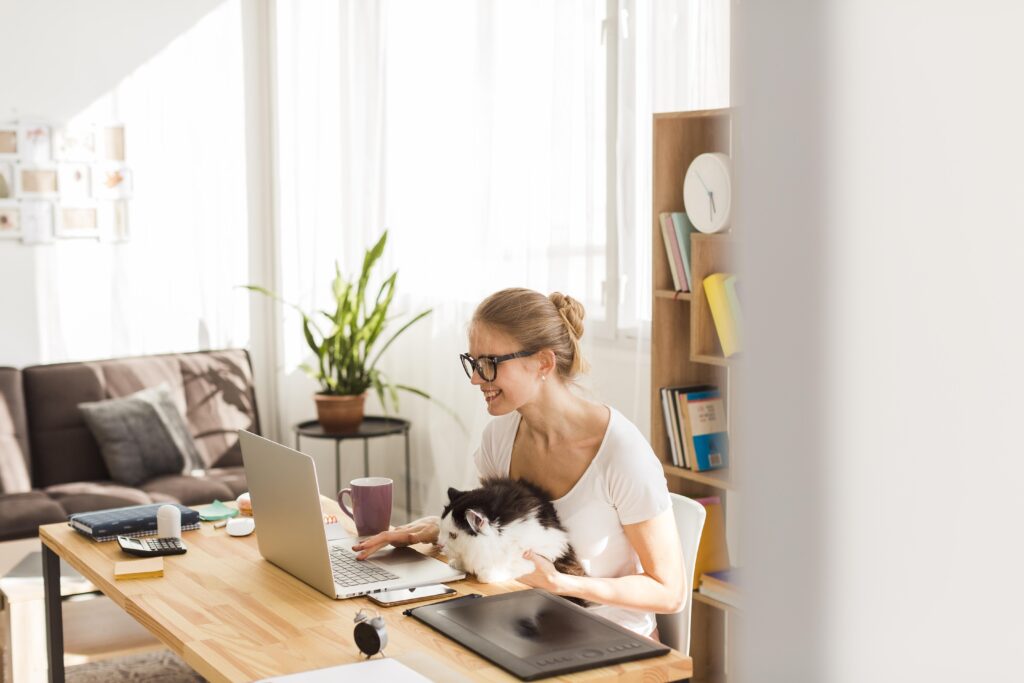 Side view of woman at desk working with her cat remotely